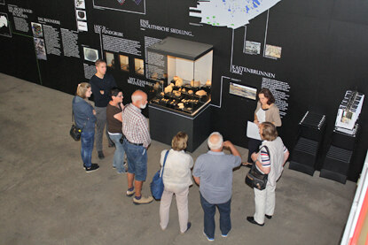 Dr. S. Kretschmer (rechts im Bild) führt Besucherinnen und Besucher durch die Geschichte der Jungsteinzeit am Beupiel der anschaulichen Ausstellung in Groitzsch-Großstolpen.