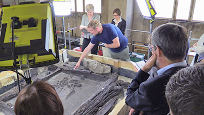 Grabungsleiter Frank Schell zeigt den Besuchern das im Brunnen gefundene Skelett einer kleinen Ziege.
