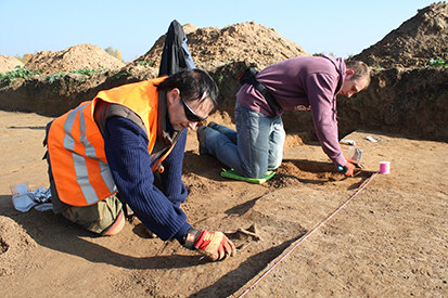 Vorsichtig legen die Mitarbeiter der Ausgrabung die Überreste eines Urnengrabes frei.