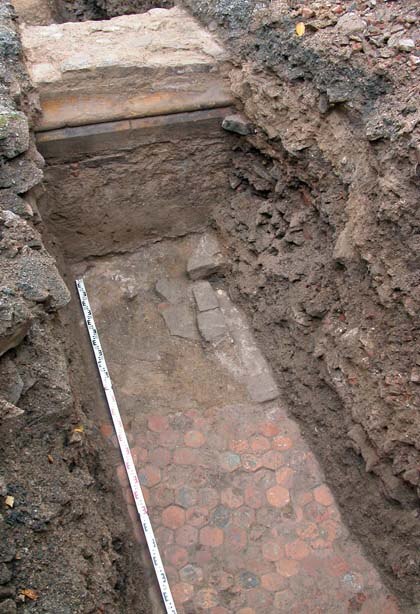 Blick auf die nördliche Außenmauer der Kirche mit dem Sockelprofil. Davor die Fußbodenplatten des Klausurgebäudes.