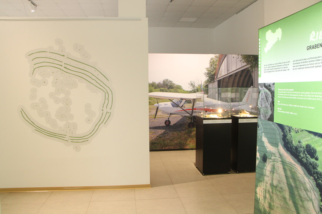 Blick in die Ausstellung mit der Wandgrafik eines Grabenwerkes